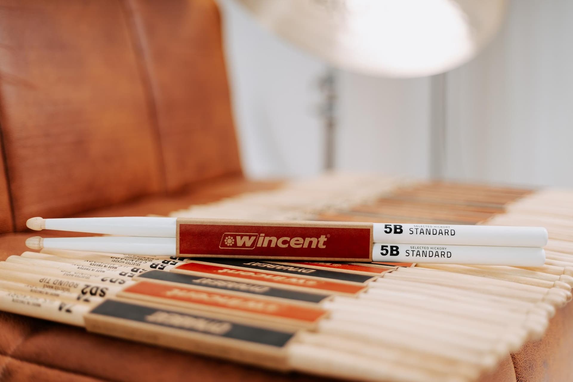 Baquetas Wincent sobre o sofá de couro, com um prato ao fundo