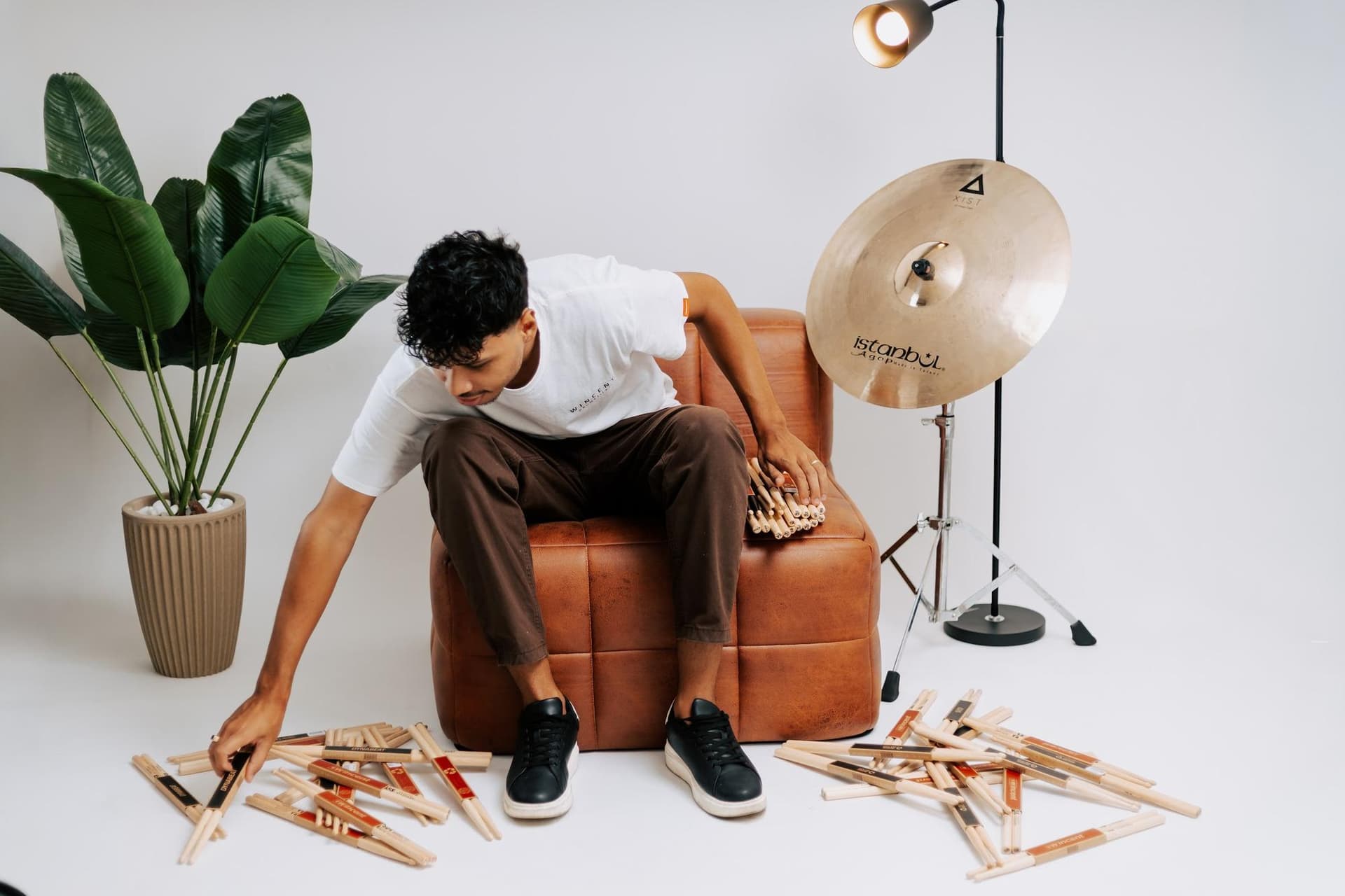 Daniel recolhendo baquetas espalhadas ao lado de um prato Istanbul Agop